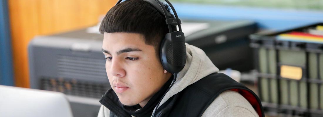 Student wearing headphones and using a computer in class